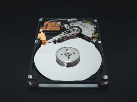 Disassembled open hard disk drive HDD of computer or laptop lies on dark matte surface. Сomputer hardware and equipment. Harddisk data storage.