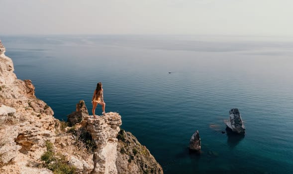 Woman travel sea. Happy tourist taking picture outdoors for memories. Woman traveler looks at the edge of the cliff on the sea bay of mountains, sharing travel adventure journey.