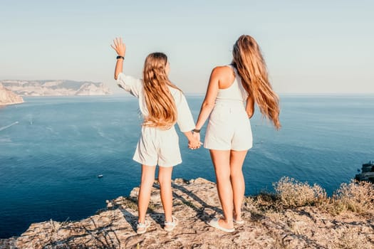 Close up portrait of mom and her teenage daughter hugging and smiling together over sunset sea view. Beautiful woman relaxing with her child.