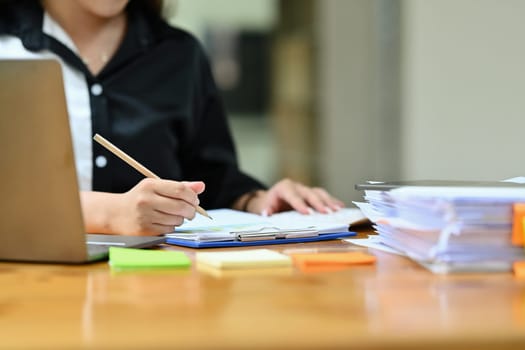 Cropped image of professional businesswoman writing business strategy, signing a contract at working desk.