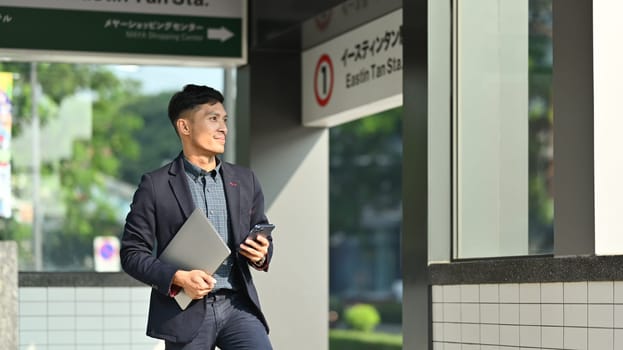 Businessman in full suit using smartphone in subway station during his morning commute.