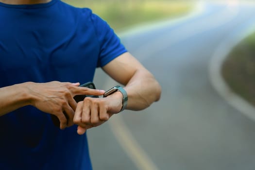 Cropped shot of male runner checking smartwatch to monitor training results. Technology health, wellness concept.