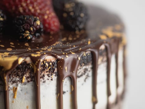 studio shot of chocolate frosted dripped icing cup cake with sweet fruit topping and golden brush strokes