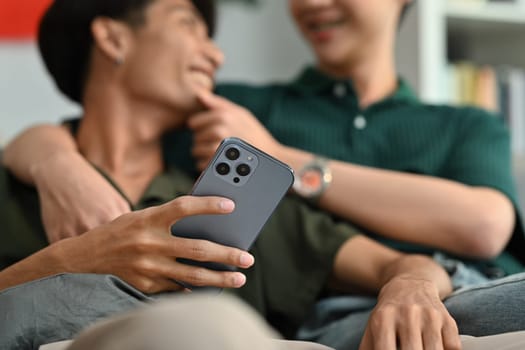 Closeup shot of man holding smartphone and talking with his boyfriend. LGBT, love and lifestyle relationship concept.