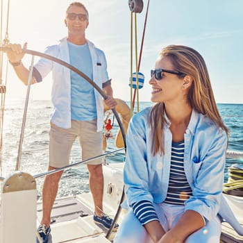 Cruise, ocean and couple for holiday on yacht with sun in the summer with the waves. People, boat and vacation on water for transport with the sunshine for freedom in nature with happiness