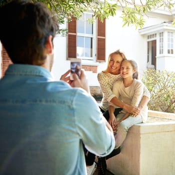 Happy family house, outdoor hug and phone photo of Mothers Day kid, child or girl with mom, mama or woman. Dad, bond and people enjoy quality time together in backyard garden, embrace and smile.