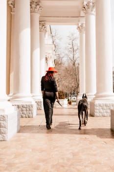 A photo of a woman and her Great Dane walking through a town, taking in the sights and sounds of the urban environment.