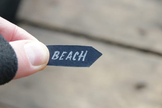 Beach idea. A hand holds a pointer with the inscription beach on a vintage background.