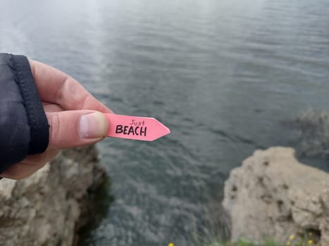 Beach idea. A hand holds a pointer with the inscription beach on a vintage background.