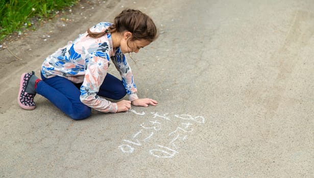 Children draw equations on the pavement with chalk. Selective focus. Kid.