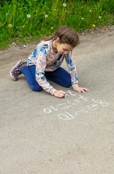 Children draw equations on the pavement with chalk. Selective focus. Kid.