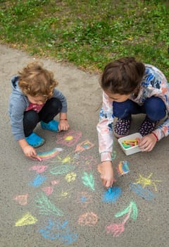 Children draw with chalk on the pavement. Selective focus. Kid.