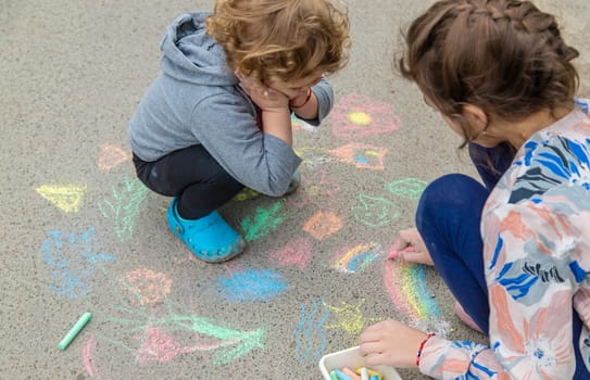 Children draw with chalk on the pavement. Selective focus. Kid.