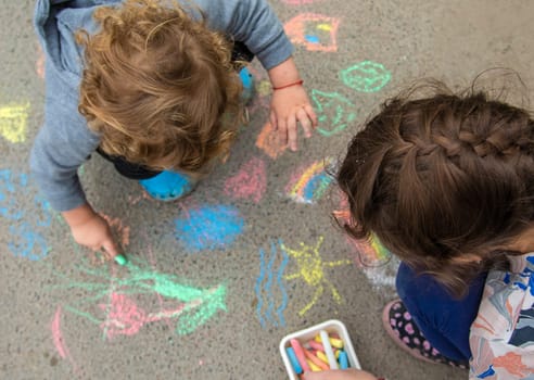 Children draw with chalk on the pavement. Selective focus. Kid.