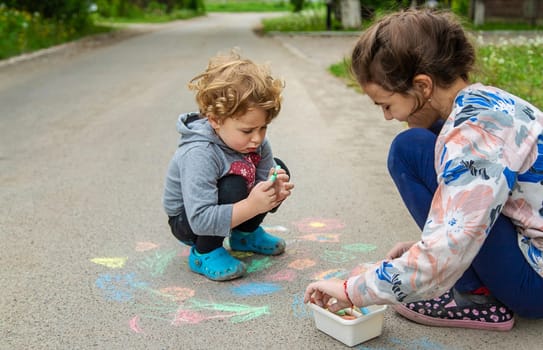 Children draw with chalk on the pavement. Selective focus. Kid.