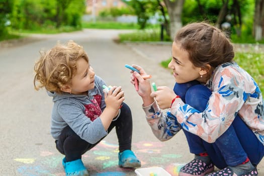 Children draw with chalk on the pavement. Selective focus. Kid.