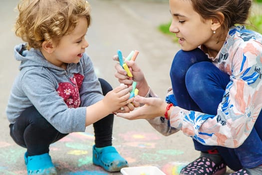 Children draw with chalk on the pavement. Selective focus. Kid.