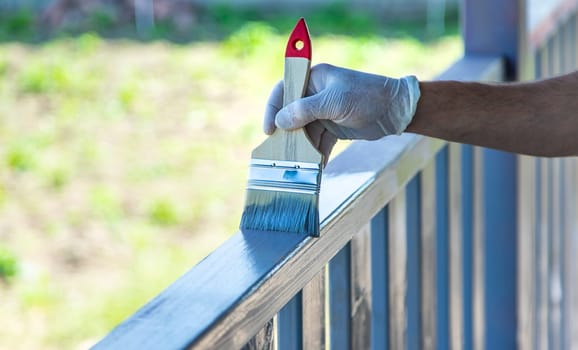 Painting a wooden board with a gray brush. Selective focus. Nature.