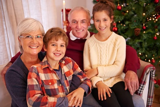 Christmas, senior couple and couch with grandchildren, happiness and relax for festive season at home. Xmas, love and elderly man with mature woman, grandkids or happy with smile, content or portrait.