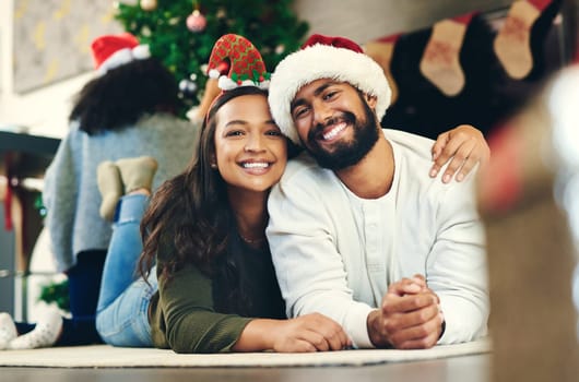 Love, happy and portrait of a couple at christmas party relaxing on the floor together in living room. Happiness, smile and young man and woman at festive holiday event for xmas celebration at house