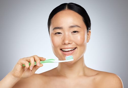 Brushing teeth, asian woman beauty and dental wellness, health and cleaning cosmetics on studio background. Happy young Japanese model face portrait, toothpaste on toothbrush and healthy mouth breath.