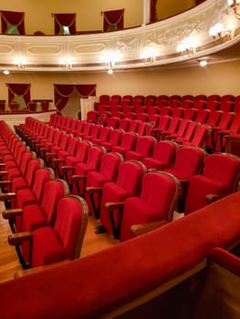 Close-up of traditional, classic empty chairs upholstered in red velvet, the interior of the theater.