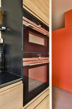 a kitchen with an oven and red cabinetd cupboards in the wall behind it, there is a microwave on the stove