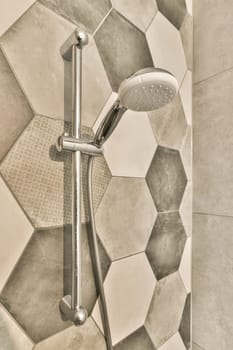 a shower with hexagon tiles on the wall behind it and a hand held shower head in the corner