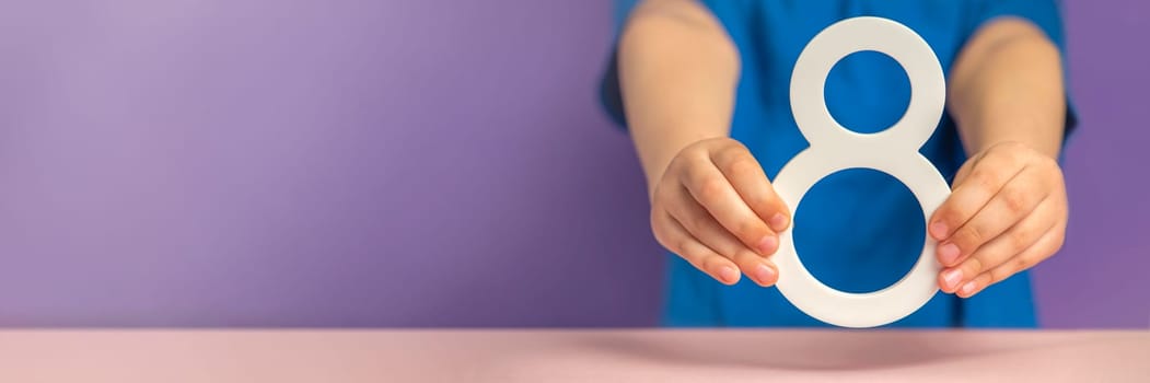 Number 8 in hand. A hand holds a white number eight on a purple background, eight percent per annum. The concept of international women's day on March 8. Advertising banner or greeting card