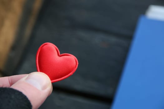 Human hand holding red toy heart. Valentine's Day concept.