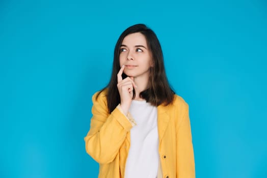 Thoughtful and Stylish Woman in Trendy Clothing - Portrait of an Attractive Young Lady with a Skeptical Gaze, Isolated on Blue Background - Copy Space Available.