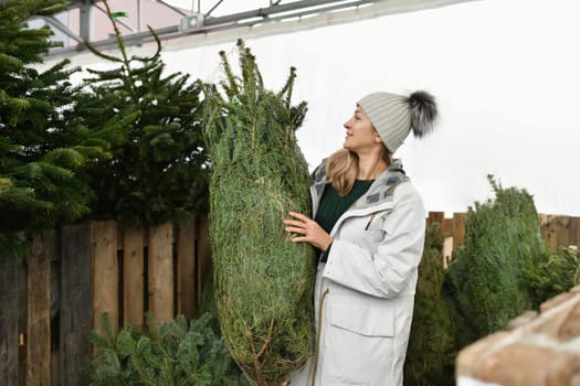 A woman buying a Christmas tree in the market.