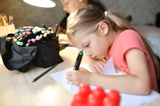 Girl draws with colorful felt-tip pens