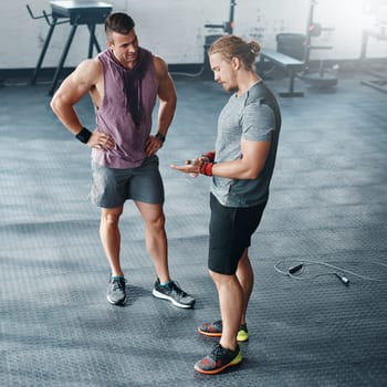 Discussing ways to better their routine. two young men chatting at the gym