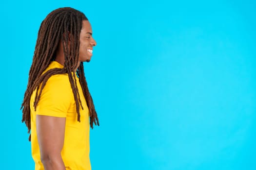 Profile of a latin man with dreadlocks looking ahead in studio with blue background