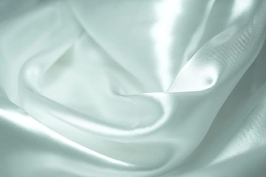 White satin fabric background with wavy soft folds for selling product. White Texture - light Wavy Glossy Silk Drapery. Shiny smooth fabric. Elegant background for design.