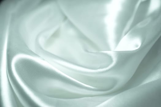 White satin fabric background with wavy soft folds for selling product. White Texture - light Wavy Glossy Silk Drapery. Shiny smooth fabric. Elegant background for design.