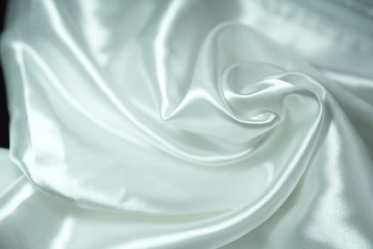 White satin fabric background with wavy soft folds for selling product. White Texture - light Wavy Glossy Silk Drapery. Shiny smooth fabric. Elegant background for design.