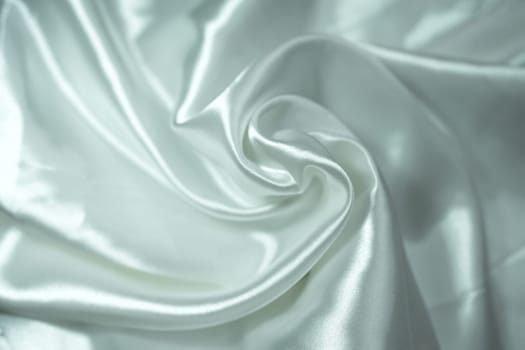 White satin fabric background with wavy soft folds for selling product. White Texture - light Wavy Glossy Silk Drapery. Shiny smooth fabric. Elegant background for design.