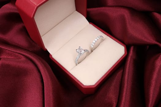 Luxury jewelryFine jewelry as diamond ring on white gold or platinum setting with red satin fabric background. Jewelry Luxury shop concept for engagement couple lover