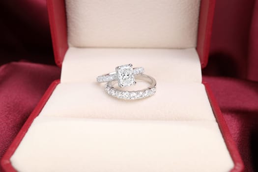 Luxury jewelryFine jewelry as diamond ring on white gold or platinum setting with red satin fabric background. Jewelry Luxury shop concept for engagement couple lover