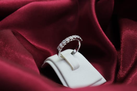 Luxury jewelryFine jewelry as diamond ring on white gold or platinum setting with red satin fabric background. Jewelry Luxury shop concept for engagement couple lover