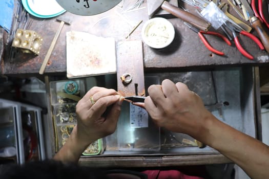 Old wood table for goldsmith with gold ring. Jeweler in Asia. Ancient and handmade jewelry work