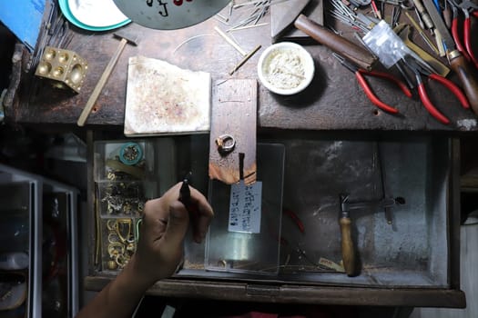 Old wood table for goldsmith with gold ring. Jeweler in Asia. Ancient and handmade jewelry work