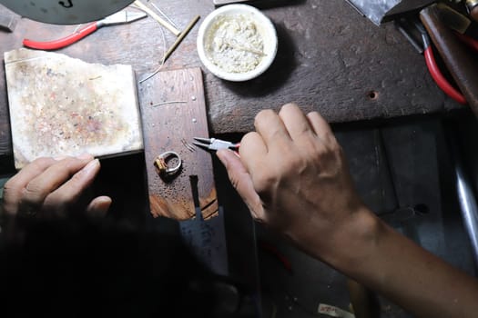 Old wood table for goldsmith with gold ring. Jeweler in Asia. Ancient and handmade jewelry work