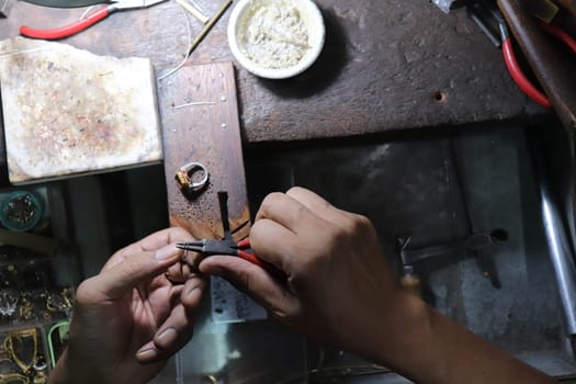 Old wood table for goldsmith with gold ring. Jeweler in Asia. Ancient and handmade jewelry work