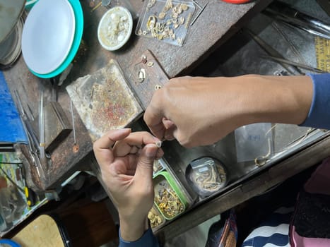 Old wood table for goldsmith with gold ring. Jeweler in Asia. Ancient and handmade jewelry work