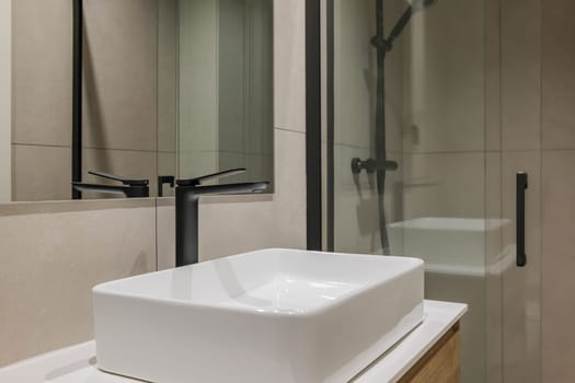 Close-up of white sink with black faucet and mirror. Interior of modern style bathroom in refurbished apartment
