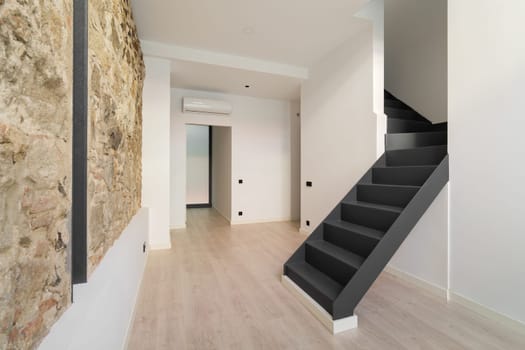 Mix of new and old architecture. Refurbished apartment with restored ancient wall left from old city buildings. Interior of empty renovated room in a duplex flat