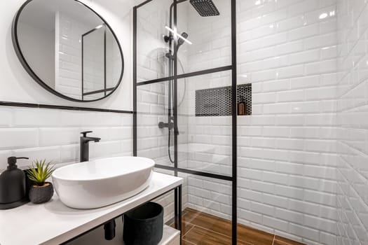 Simple bathroom with black shower, round mirror and classic white tiles.